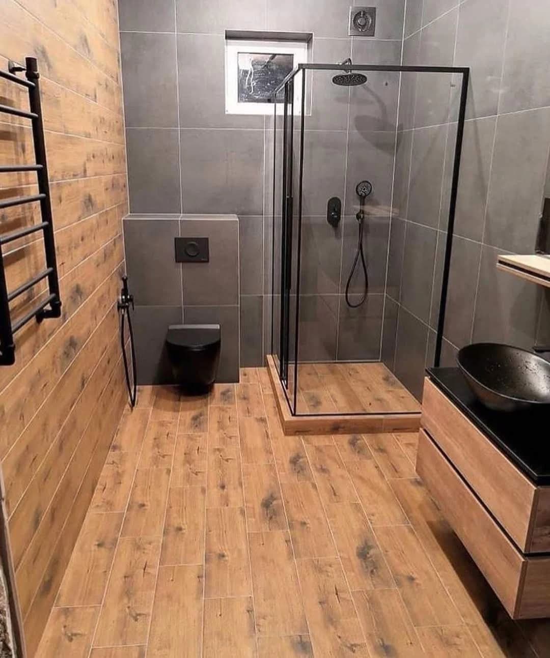 Ahşap görünümlü yüzeyler ve siyah detaylarla tamamlanan banyo